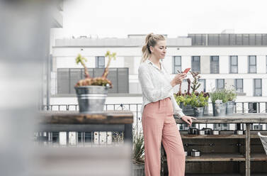 Lässige Geschäftsfrau mit Mobiltelefon auf der Dachterrasse - UUF18553