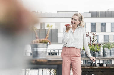 Happy casual businesswoman using cell phone on roof terrace - UUF18556