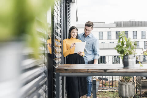 Lässiger Geschäftsmann und Frau mit Dokumenten treffen sich auf der Dachterrasse, lizenzfreies Stockfoto