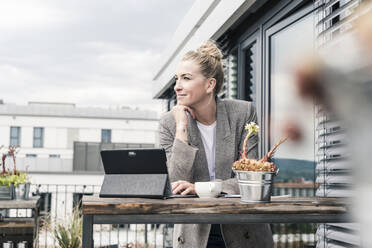 Businesswoman with tablet on roof terrace having a break - UUF18569