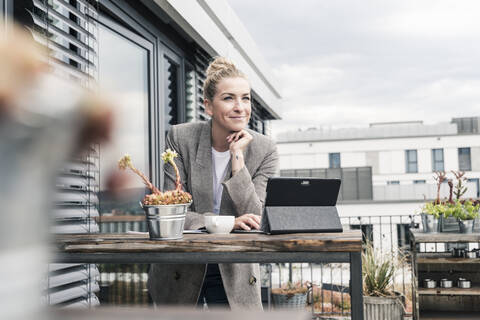 Geschäftsfrau mit Tablet auf der Dachterrasse, die eine Pause macht, lizenzfreies Stockfoto