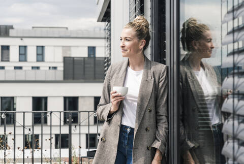 Businesswoman with coffee cup standing on roof terrace stock photo