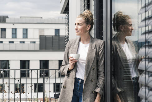 Geschäftsfrau mit Kaffeetasse auf der Dachterrasse - UUF18576