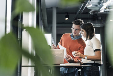 Casual businessman and woman with laptop meeting in office - UUF18590