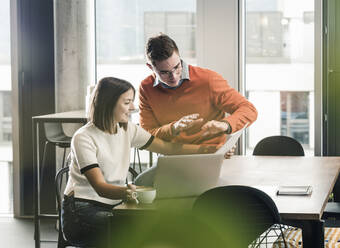 Casual businessman and woman with laptop meeting in office - UUF18595