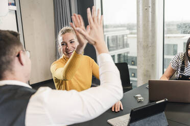 Happy businessman and woman high fiving in office - UUF18646