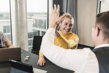 Happy businessman and woman high fiving in office - UUF18647