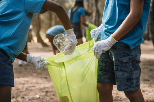 Close-up of volunteering children collecting garbage in a park - JCMF00113