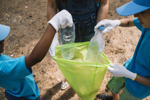 Close-up of volunteering children collecting garbage in a park - JCMF00117