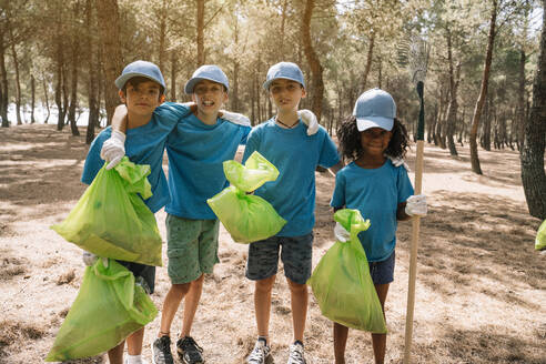 Group portrait of volunteering children collecting garbage in a park - JCMF00121