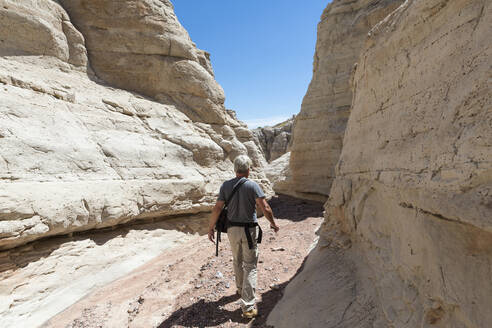 Older Caucasian man exploring rock formations - BLEF13895