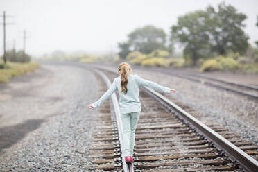 Kaukasisches Mädchen balanciert auf Eisenbahnschienen - BLEF13900