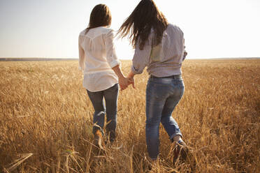 Caucasian women holding hands in rural field - BLEF13910