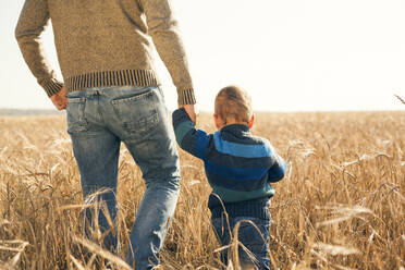 Kaukasischer Vater und Sohn gehen in einem ländlichen Feld spazieren - BLEF13921