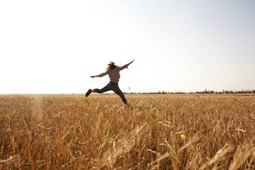 Kaukasische Frau springt vor Freude in einem ländlichen Feld - BLEF13924