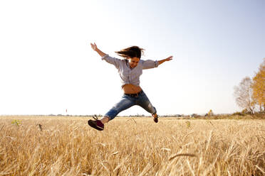 Caucasian woman jumping for joy in rural field - BLEF13925