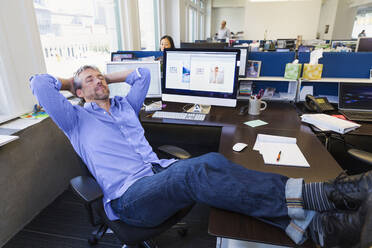 Businessman relaxing at desk in office - BLEF13993