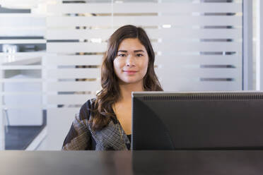 Gemischtrassige Geschäftsfrau arbeitet am Computer im Büro - BLEF14000