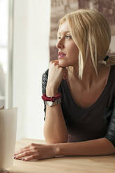 Woman sitting alone at table in cafe - BLEF14013