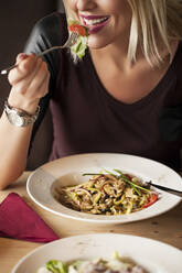 Woman eating bowl of food in cafe - BLEF14019