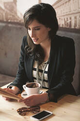 Frau liest mit einer Tasse Kaffee in einem Cafe - BLEF14026