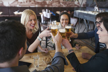 Freunde stoßen mit Bier im Café an - BLEF14029