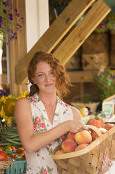 Caucasian carrying basket of peaches at farmers market - BLEF14093