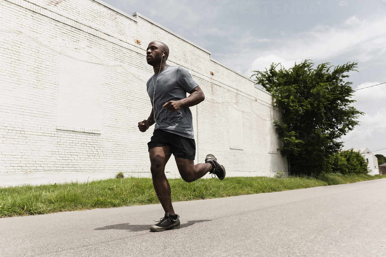 Black man running on city street stock photo