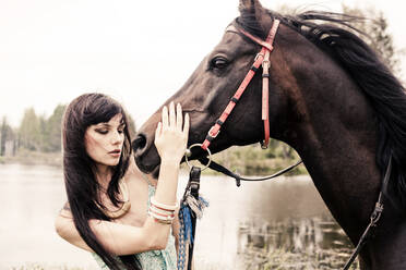 Kaukasische Frau streichelt Pferd im Freien - BLEF14130