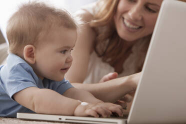 Kaukasische Mutter und Sohn benutzen Laptop auf dem Boden - BLEF14163