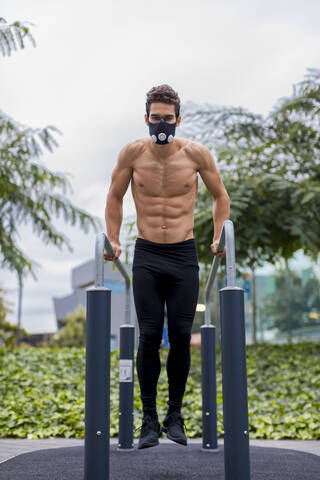 Sportler beim Training am Barren in der Stadt, mit Atemmaske, lizenzfreies Stockfoto