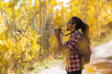 Gemischtrassiger Wanderer beim Fotografieren im Wald - BLEF14193