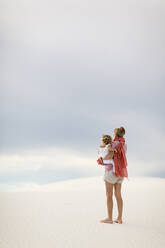 Caucasian mother holding son on sand dune - BLEF14213