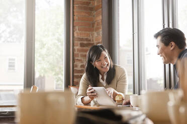 Chinesische Frau gibt ihrem Mann im Café ein digitales Tablet - BLEF14250