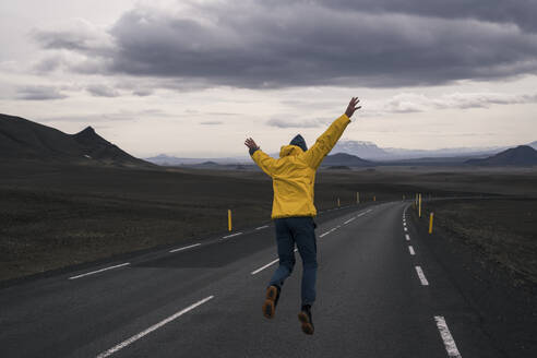 Happy man jumping for joy on an empty road, Iceland - UUF18654