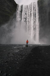 Mature man watching Skogafoss waterfalls, Iceland - UUF18663