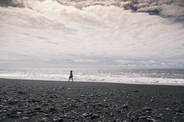 Young woman walking on barefoot on a lava beach in Iceland - UUF18669