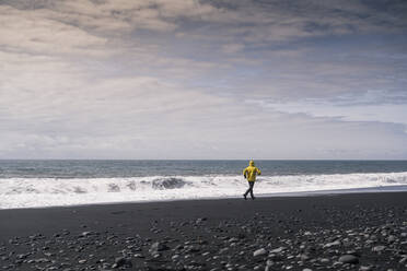 Älterer Mann läuft auf einem Lavastrand in Island - UUF18671