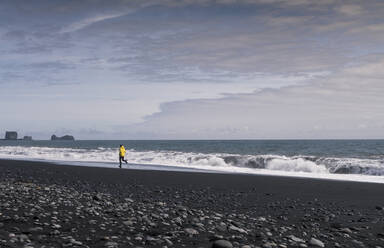 Älterer Mann läuft auf einem Lavastrand in Island - UUF18672