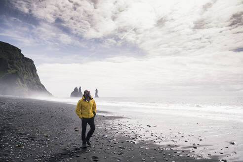 Mature man walking on a lava beach in Iceland - UUF18677