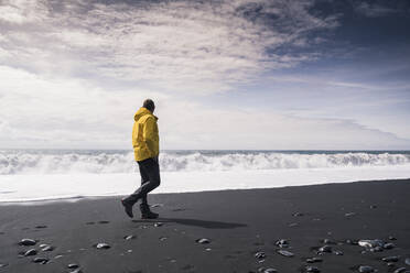 Älterer Mann, der an einem Lavastrand in Island spazieren geht - UUF18680