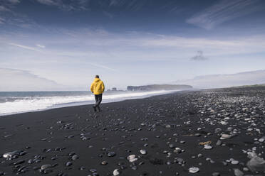 Mature man walking on a lava beach in Iceland - UUF18681