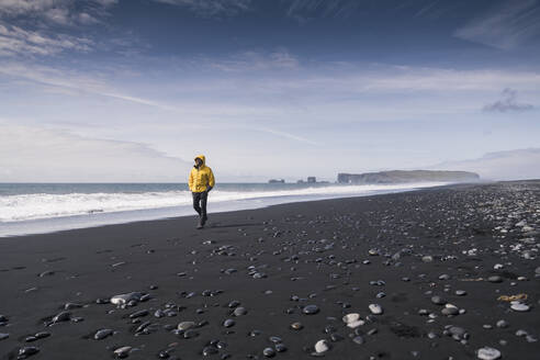 Mature man walking on a lava beach in Iceland - UUF18682