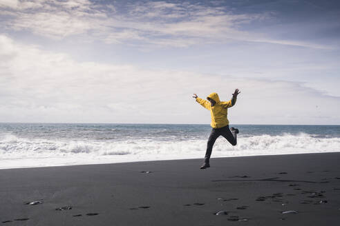 Älterer Mann springt vor Freude an einem Lavastrand in Island - UUF18684