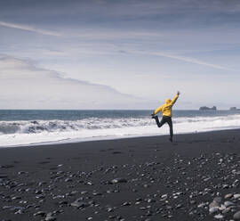 Mature man jumping for joy on a lava beach in Iceland - UUF18685