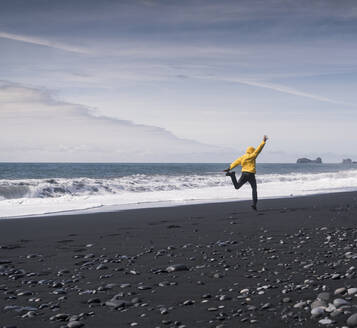 Mature man jumping for joy on a lava beach in Iceland - UUF18685