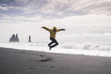 Mature man jumping for joy on a lava beach in Iceland - UUF18686