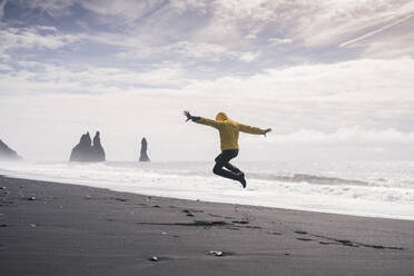 Mature man jumping for joy on a lava beach in Iceland - UUF18687