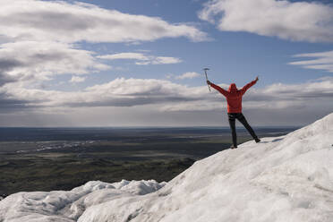 Mature man standing in Skaftafell National Park on Vatnajokull glacier, Iceland, holding ice ax - UUF18699