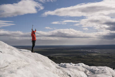 Mature man standing in Skaftafell National Park on Vatnajokull glacier, Iceland, holding ice ax - UUF18700